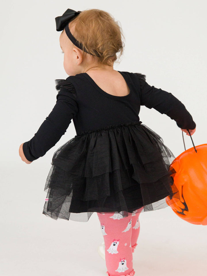 Toddler in black flutter tulle long sleeve romper with headband bow, holding orange pumpkin bucket, pink ghost tights.